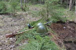 un casco de guerra y una ametralladora yacen al borde de la trinchera foto