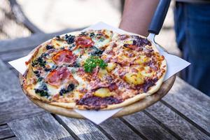 Homemade pizza served on wood plate photo