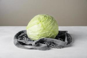 Head of white cabbage lie on the surface in environmentally friendly mesh bag photo