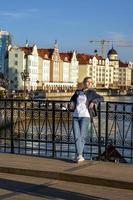 Young blonde stands on bridge against backdrop of a beautiful city embankmen photo