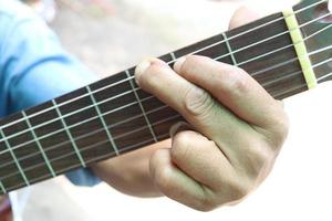 Hand is playing guitar. Fingers are pressing on strings of guitar. photo