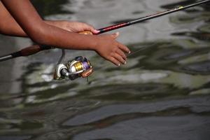 Hand is catching fishing rod and water background. photo
