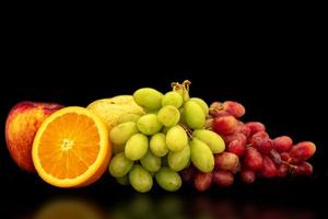 Orange, grapes, apple and pyrus pyriflora on a black background. photo