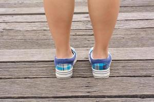 Canvas sneakers on feet on the wooden bridge photo