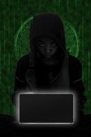 Hacker boy are hacking through the laptop on green symbols background. photo