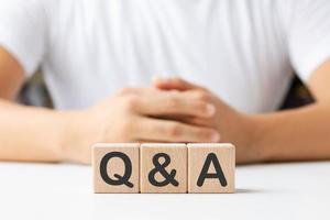 Hand holding Q and A words with wooden cube blocks , answers, ask questions, information,FAQ. photo