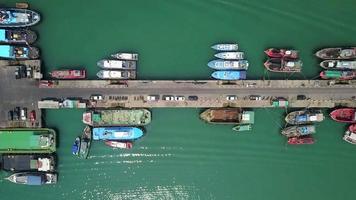 vista aérea del muelle de pescadores que tiene muchos barcos de pesca anclados para el transporte de mariscos y suministros tierra adentro video