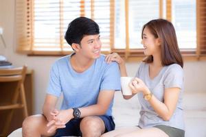 Beautiful portrait young asian couple give a cup of coffee with smiling and happy together, family take care with health, man give water woman in the bedroom, lifestyle concept.