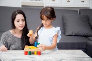 la madre y el niño juegan juntos en la sala de estar en casa, el niño desarrolla el aprendizaje para la educación con actividad con la familia, la madre enseña a la hija con diversión y habilidad en el pasatiempo. foto