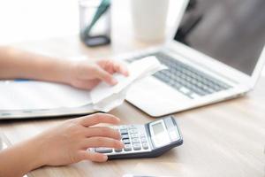 mujer de primer plano calculando los gastos del hogar y escribiendo un cuaderno en el escritorio, niña revisando la factura y el estrés y la nota, la preocupación femenina por la deuda y el concepto de impuestos, finanzas y negocios. foto