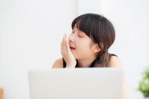 beautiful young freelance asian woman working bored and tired on laptop computer at the office, girl lazy sleepy and yawning on notebook, female secretary with exhausted, business concept. photo