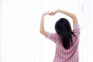 Beautiful of portrait young asian woman stretch and relax in bed after wake up morning at bedroom, new day and resting for wellness, back view, lifestyle concept. photo