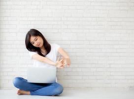 Beautiful portrait young asian woman sitting with laptop stretch and exercise relax after work success on cement concrete background, modern office with copy space, freelance business concept. photo