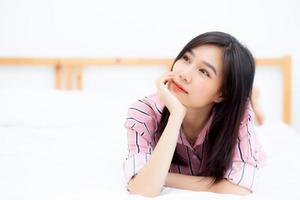 hermoso retrato joven mujer asiática acostada y sonriendo mientras se despierta con el amanecer en los buenos días, chica con feliz, estilo de vida y concepto de relajación. foto