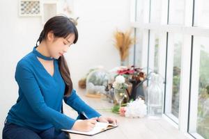 Beautiful portrait young asia woman writer writing on notebook or diary with happy, lifestyle of asian girl is student, female planning working, education and business concept. photo
