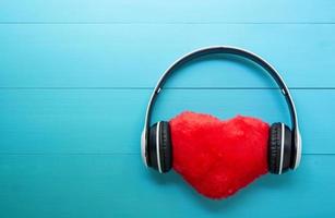 auriculares y música en forma de corazón sobre fondo de madera azul, auriculares con radio de audio, día de san valentín, concepto de amor y vacaciones. foto