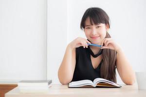 Beautiful portrait young asian woman smiling sitting study and learning writing notebook and diary in the living room at home, girl homework, businesswoman working on table, education concept. photo
