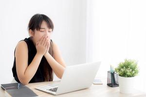 beautiful young freelance asian woman working bored and tired on laptop computer at the office, girl lazy sleepy and yawning on notebook, female secretary with exhausted, business concept. photo