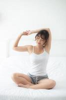 Beautiful of portrait young asian woman stretch and relax in bed after wake up morning at bedroom, new day and resting for health and wellness, back view, lifestyle concept. photo