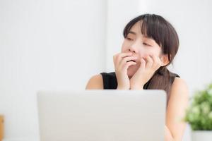 beautiful young freelance asian woman working bored and tired on laptop computer at the office, girl lazy sleepy and yawning on notebook, female secretary with exhausted, business concept. photo