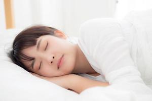 bella joven asiática durmiendo en la cama con la cabeza en la almohada cómoda y feliz. chica con relax por concepto de salud. foto