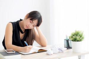 Beautiful asian woman tired and stressed with writing overworked at desk, girl with worried not idea with notebook and crumpled paper at office, freelance and business concept. photo