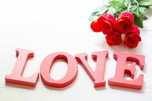 Regalo presente con flor de rosa roja y palabra amor en mesa de madera, 14 de febrero con concepto romántico de vacaciones de San Valentín. foto