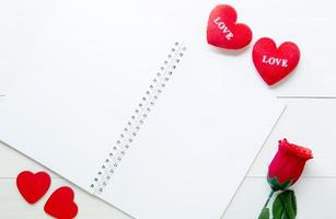 Present gift with red rose flower and heart shape and notebook on wooden table, 14 February of love day with romantic, copy space with note or diary writing text for you, valentine holiday concept photo