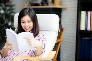 Beautiful of portrait young asian woman relax sitting reading book in living room at home, girl study literature, education and llifestyle concept. photo