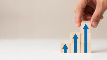 Business success idea, corporate growth process, wooden block arrangement by hand step by step with up arrow. photo