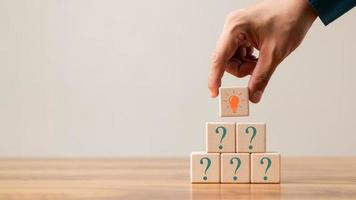 Creative concept. Think different, wooden cube with question mark and light bulb sign. photo