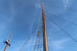 Sailing ship mast against the blue sky on some sailing boats with rigging details. photo