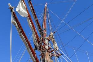 Sailing ship mast against the blue sky on some sailing boats with rigging details. photo