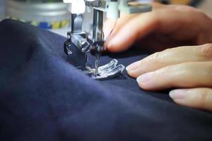 Sewing concept. Female hands working at a modern sewing machine with some fabrics and textiles photo