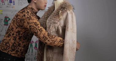 Nahaufnahme eines jungen asiatischen Modedesigners, der Maßband auf Mannequin-Modell im Studio misst. Startup-Kleinunternehmer. KMU-Marketing und Unternehmerkonzept. video