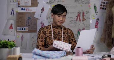 Portrait of fashion designer man checking the quality and design in the studio. Startup small businessman is in process of creating a new clothes collection. video