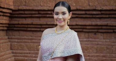 retrato de mulher tailandesa em traje tradicional, olhando para a câmera e sorrindo no antigo templo. video