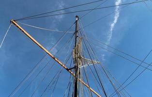 Sailing ship mast against the blue sky on some sailing boats with rigging details. photo