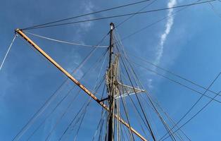 Sailing ship mast against the blue sky on some sailing boats with rigging details. photo