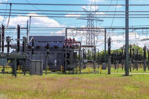 transformador electrico distribución de energía eléctrica en una gran subestación con muchas líneas eléctricas en un día soleado foto