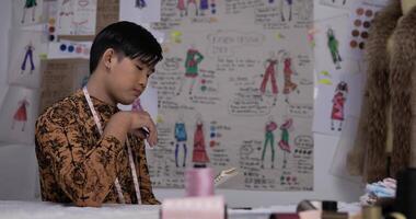 Portrait of Thoughtful Asian clothing designer man working in the studio. Startup small businessman is in process of creating a new clothes collection. video