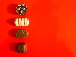 Very tasty chocolates from chocolate and nougat on a red background. photo