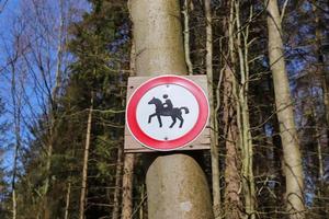 señal de prohibición para caballos y jinetes atados a un árbol en un bosque. foto