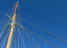Sailing ship mast against the blue sky on some sailing boats with rigging details. photo