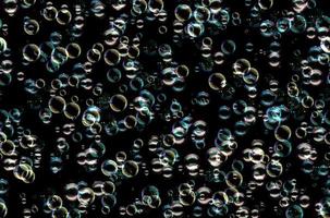 Many colorful soap bubbles on a black background. Concept texture pattern photo