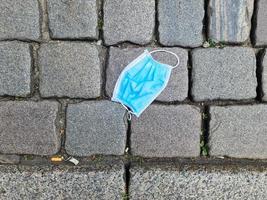 Close-up image of a surgical mask dropped and abandoned in the street during the corona virus crisis photo