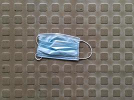 Close-up image of a surgical mask dropped and abandoned in the street during the corona virus crisis photo