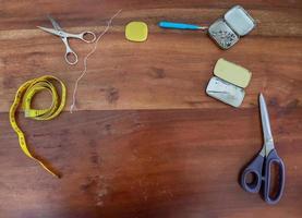 Sewing concept. Different sewing accessoires on a brown wooden background. photo