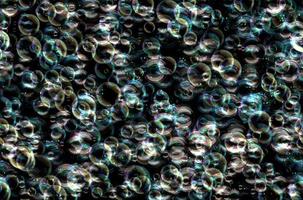 Many colorful soap bubbles on a black background. Concept texture pattern photo