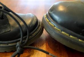 Big and small old black leather shoe on a wooden floor photo